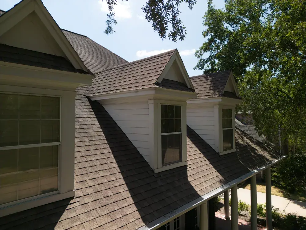 Brown architectural shingle roof with three dormer windows on a two-story home.